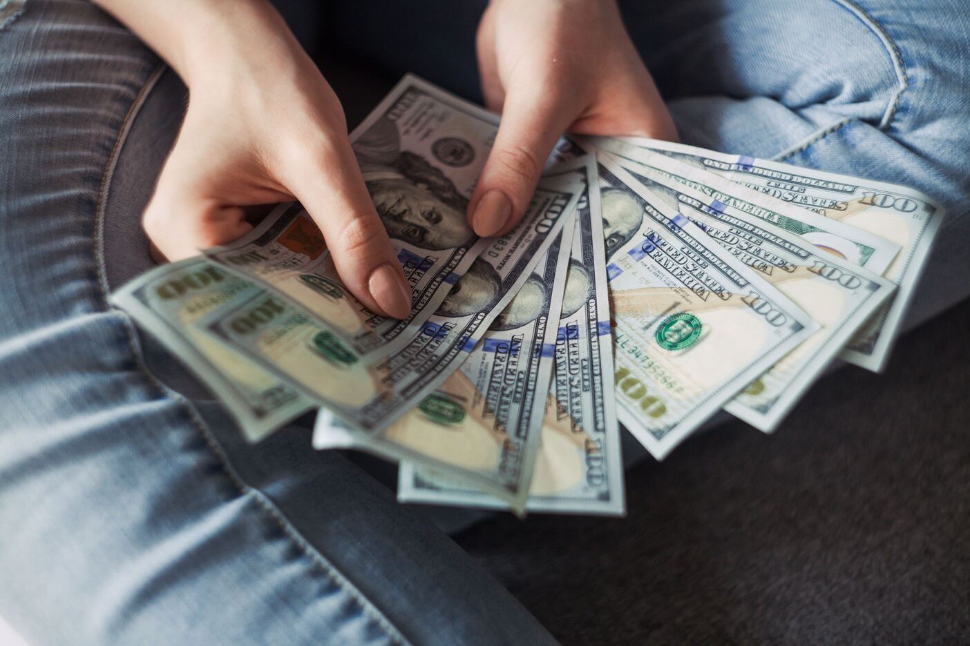 Person holding a banknote of 100 dollars